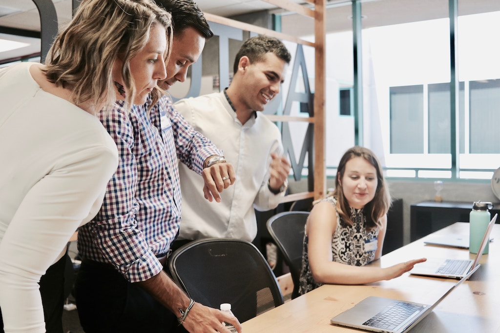 woman showing her team a presentation on her laptop